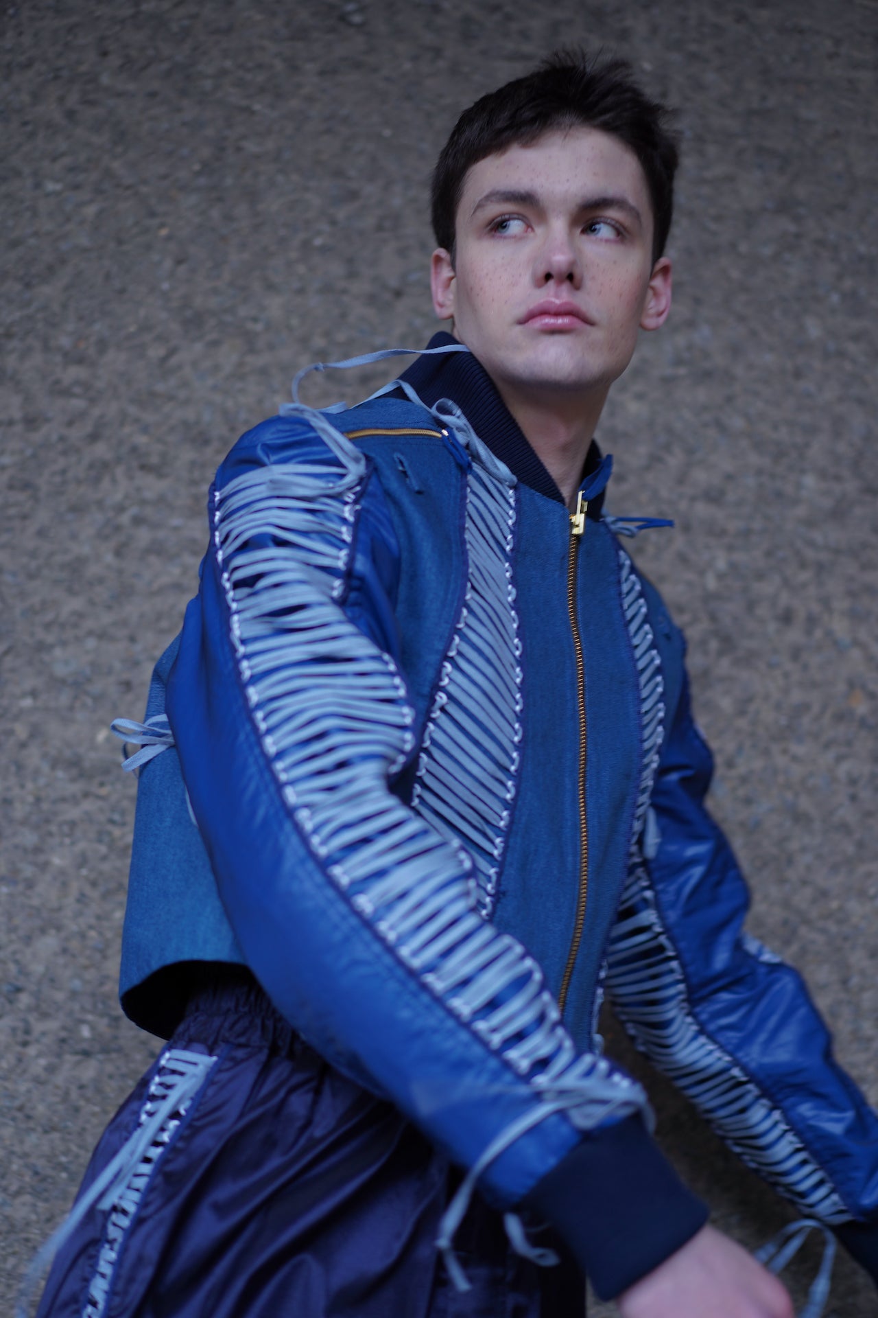 Side profile shot of model wearing YYAtomic blue denim lacing jacket.